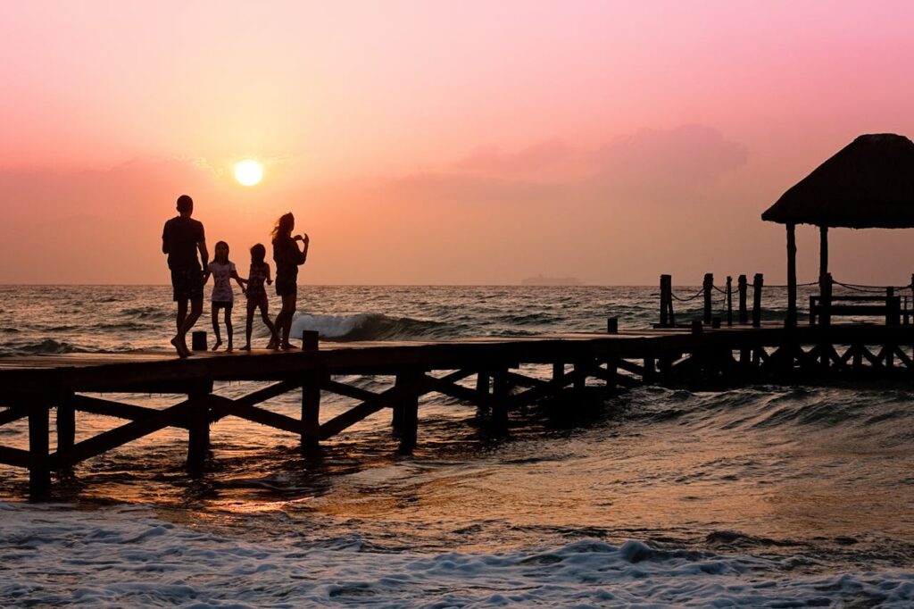 family pier man woman 39691 Silhouetted family enjoys a stroll on the beach pier at a vibrant sunset over the ocean waves.